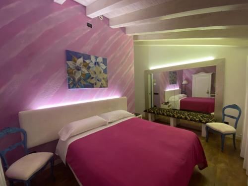 1 dormitorio con cama rosa y espejo en Romantica camere Le Fate con Vista sulle Montagne vicino a Bassano del Grappa, en Romano D'Ezzelino