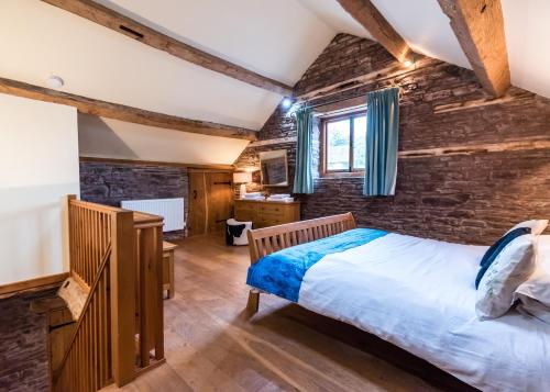 a bedroom with a bed and a brick wall at Pomona Cottage at Old King Street Llama Farm in Ewyas Harold