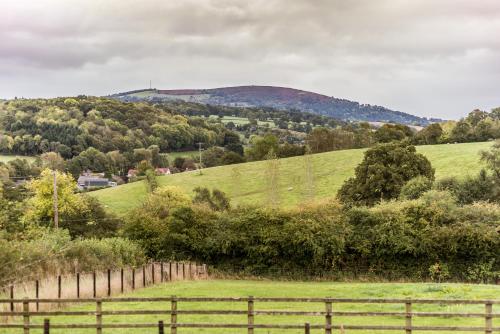 a fence in a field with a hill in the background at Pomona Cottage at Old King Street Llama Farm in Ewyas Harold