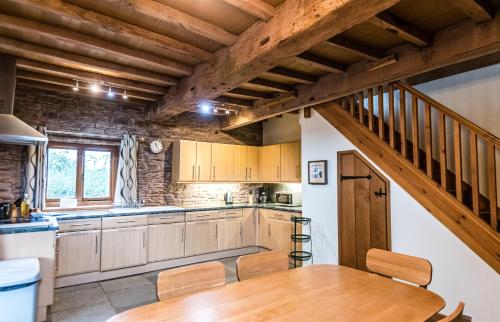 a kitchen with wooden cabinets and a wooden table at Pomona Cottage at Old King Street Llama Farm in Ewyas Harold