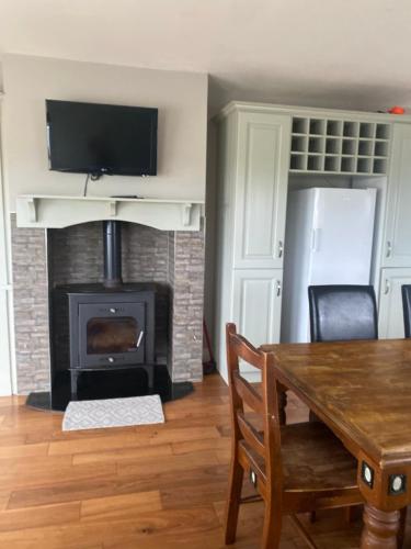 a living room with a fireplace and a wooden table with chairs at Private House, Wild Atlantic Way, Spanish Point Road, Miltown Malbay in Miltown Malbay