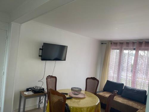 un salon avec une table et une télévision au mur dans l'établissement Grand Appartement spacieux à Évreux, à Évreux