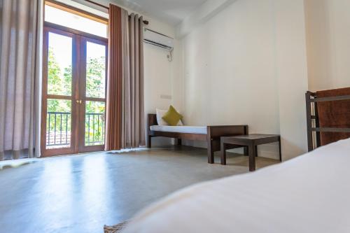 a bedroom with a bed and a desk and a window at Atrium Hiriketiya in Hiriketiya