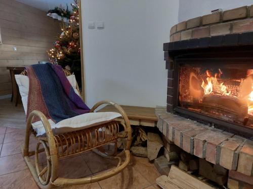 a rocking chair in front of a fireplace at Beztroska Chata Bieszczady in Mchawa