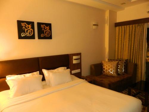 um quarto de hotel com uma cama e uma cadeira em Pramod Convention & Beach Resorts em Puri