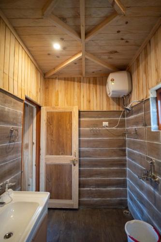 a bathroom with a sink and a toilet and a door at THE HIMALAYAN WOODS, CHAUKORI in Chaukori