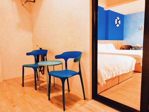 twee blauwe stoelen en een tafel voor een spiegel bij 星語采居民宿 in Magong