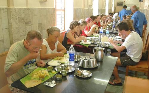 a group of people sitting at a long table eating food at Vilasam in Mahabalipuram