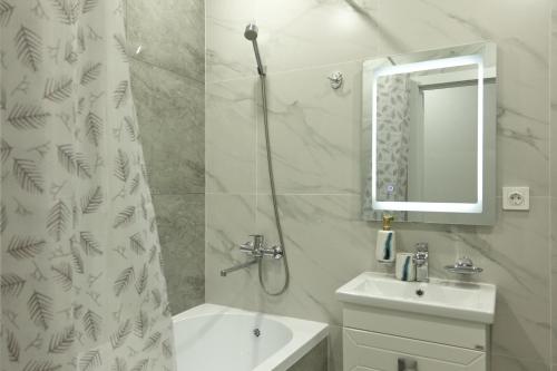 ein weißes Bad mit einem Waschbecken und einem Duschvorhang in der Unterkunft Однокомнатная с видом на мечеть в ЖК Аман in Astana