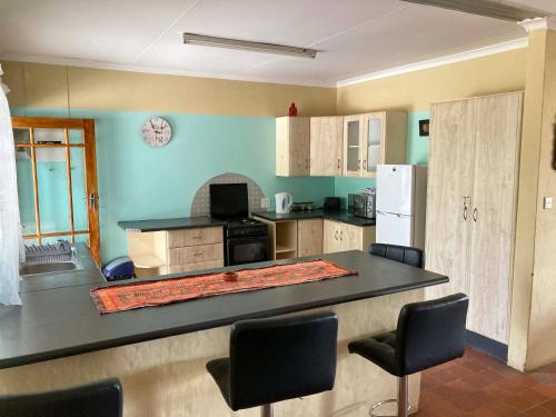 a kitchen with a counter with chairs and a refrigerator at Kalahari Homestead in Khemsbok