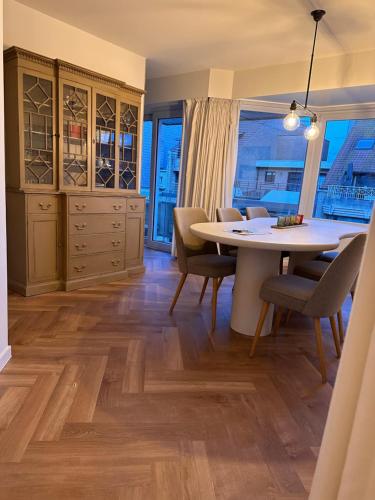 a dining room with a table and chairs and a window at Residentie Zeebries, luxe en ruim appartement met zijzicht op zee in Knokke-Heist