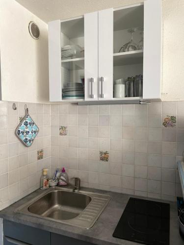 a kitchen with a sink and white cabinets at Cap d’Agde Centre port avec parking privé et belle vue port et mer in Cap d'Agde