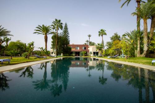 una piscina con palmeras en un parque en Villa L'oui D'or, en Marrakech