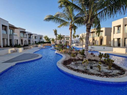 a resort with blue water and palm trees and buildings at Rivira Miko 1 in Salalah
