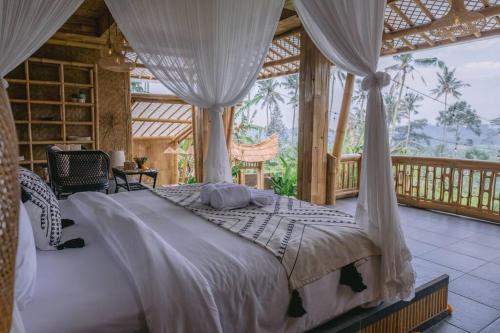 a bedroom with a canopy bed in a house at Makerti Bali~Bamboo House in Selat