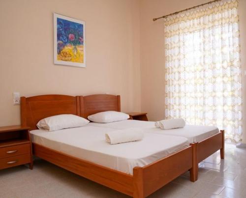 sypialnia z drewnianym łóżkiem z białą pościelą i oknem w obiekcie Villa Mare Ammoudia w Ammoudii