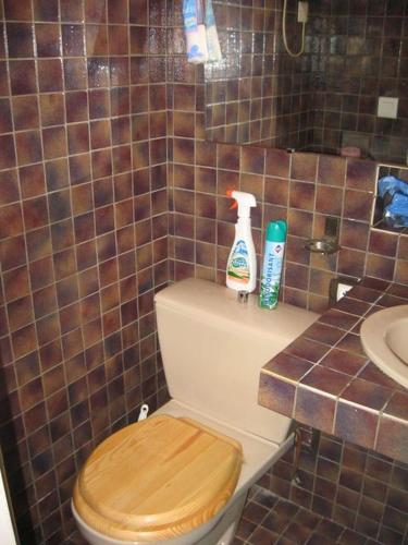 La salle de bains est pourvue de toilettes, d'un siège en bois et d'un lavabo. dans l'établissement Maison Antraigues sur Volane, à Asperjoc