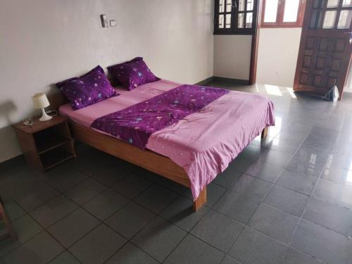 a bed with a purple comforter in a room at Bel Appartement meublé à Bastos in Yaoundé