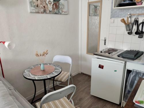 eine kleine Küche mit einem Tisch und Stühlen in einem Zimmer in der Unterkunft Le Cocon de Neptune in Arromanches-les-Bains