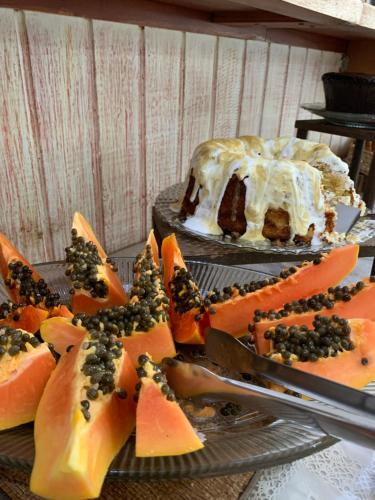 una torta appoggiata su un tavolo con un piatto di frutta di Pousada do Grilo a Santo Antônio do Pinhal
