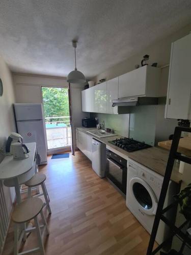 une cuisine avec des armoires blanches et une table et des chaises dans l'établissement Appartement 2 chambres Anglet, proche Biarritz, à Anglet