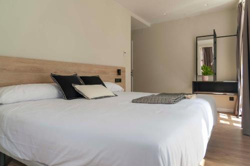 a large white bed with black pillows in a bedroom at Albatros in Puentedeume