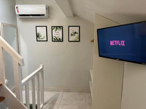 TV de pantalla plana en la pared de una escalera en Studio Apartamento Lindo na Rua das Pedras, en Búzios