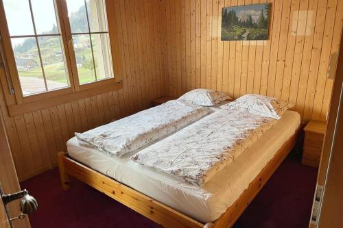 Bett in einem Holzzimmer mit Fenster in der Unterkunft Wohnung in Bergchalet in Flums