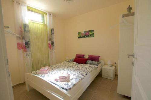 a small bedroom with a bed with red pillows at Apartman Heidi 4 Sterne in Punat