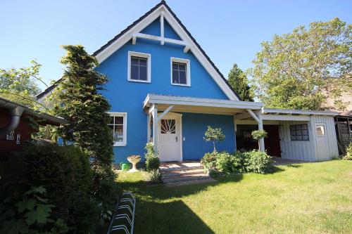 een blauw huis met een witte deur en een tuin bij Davids Ferienwohnung in Wustrow