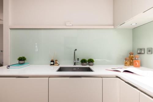 uma cozinha com armários brancos e um lavatório em Covent Garden Luxury Retreat em Londres