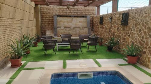 a patio with a table and chairs and a pool at AlZaeem Resort & Hotels in Barka
