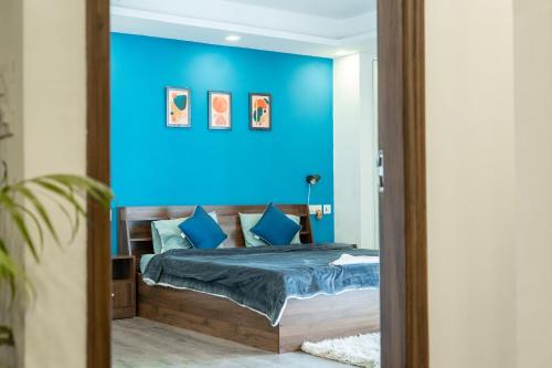 a blue bedroom with a bed with blue walls at FlxHo Uno - Serviced Apartment & Rooms - Golf Course Road in Gurgaon