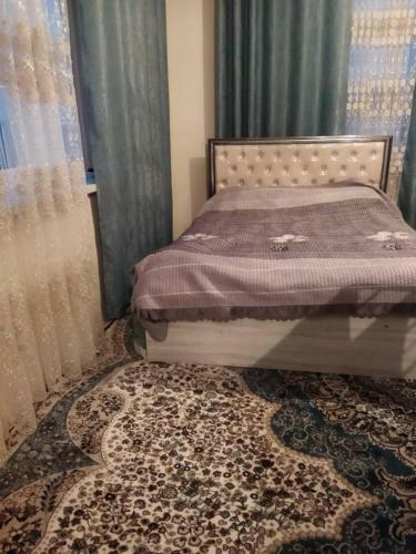 a bedroom with a bed with a rug and curtains at Buuzara Guest House in Batken