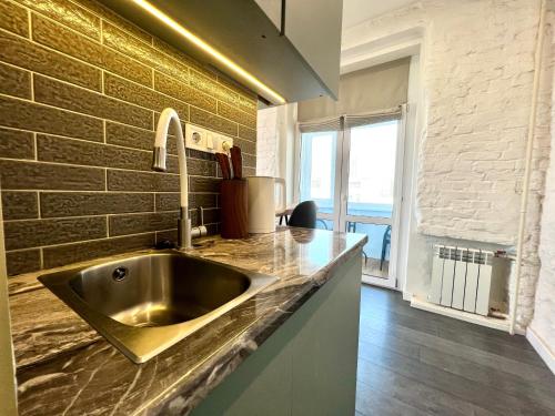 un fregadero de acero inoxidable en una cocina con una pared de ladrillo en Kyiv Panorama Apartments near Gulliver, en Kiev