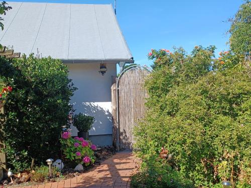 ein Haus mit einem Holztor und einer Ziegelsteinfahrt in der Unterkunft Ferienhäuschen Hinz in Wustrow