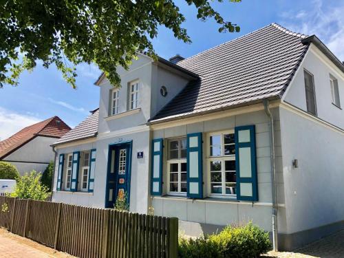una casa blanca con ventanas azules y una valla en Ferienwohnung Christl, en Wustrow