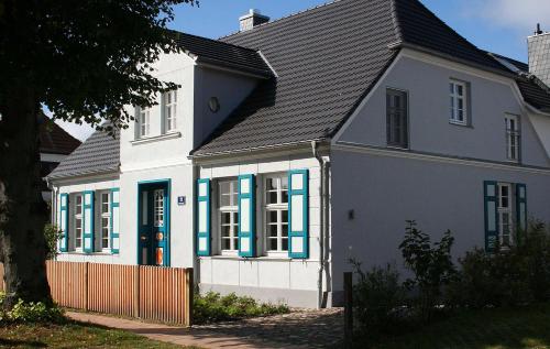 una casa blanca con ventanas azules y techo negro en Ferienwohnung Christl, en Wustrow