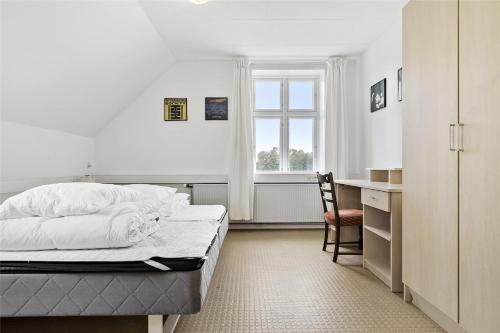 a bedroom with a bed and a desk and a window at Sigerslevhus Stevns Klint in Store Heddinge