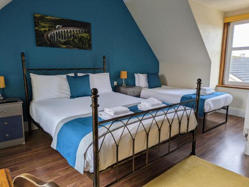 a bedroom with two beds and a blue wall at The Coo's Guest House in Inverness