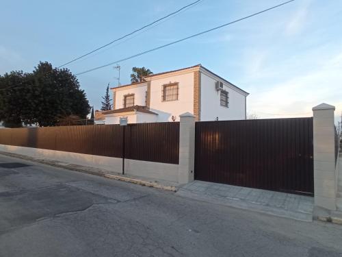 a fence in front of a white house at Casa Rural El Algarrobo in Utrera