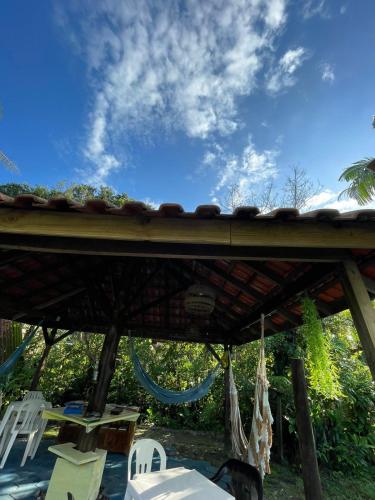 a patio with white chairs and a wooden roof at Camping e Pousada do Ade in Ilha do Mel