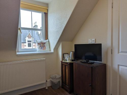 a living room with a tv and a window at The Coo's Guest House in Inverness