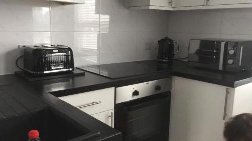 a kitchen with a black counter top with a toaster oven at LondonRooms in London