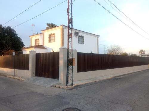 a fence in front of a white house at Casa Rural El Algarrobo in Utrera