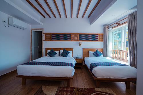 two beds in a room with two windows at Himalayan Glory Inn in Pokhara