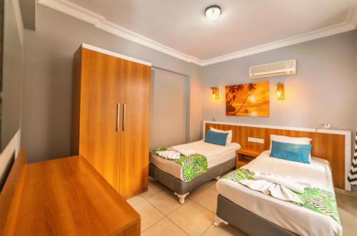 a room with two beds and a cabinet at Kleopatra ICARIA Apart Hotel in Alanya