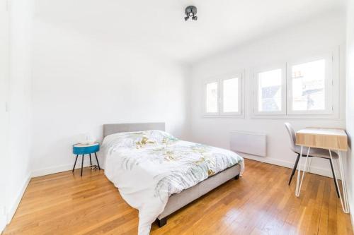 um quarto branco com uma cama e piso em madeira em @Villa au coeur de Brive@ avec jardin et garage em Brive-la-Gaillarde