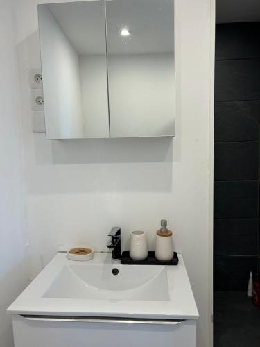 a white kitchen with a sink and a mirror at Grand T2 bis avec terrasse et vue in Portel-des-Corbières