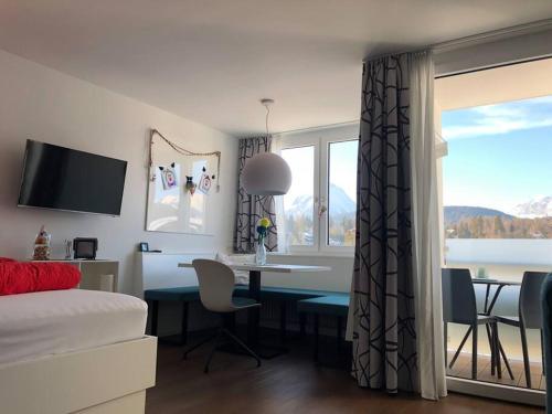 ein Schlafzimmer mit einem Schreibtisch und einem Tisch mit Stühlen und einem Fenster in der Unterkunft Sonniges Apartment mit Hallenbad und Sauna in Seefeld in Seefeld in Tirol